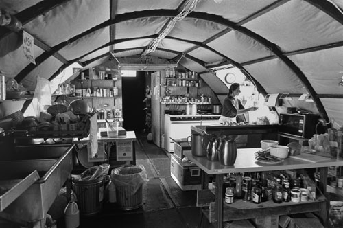 <p>Tanya Zastrow prepares lunch in the Siple Dome galley. Located 600 miles east of McMurdo, this "Jamesway" was assembled as part of a temporary camp hurriedly assembled to accommodate 50 people for the season.</p><p>"When they first flew us in it was 35 below F and cold; windy and cold. On a &rsquo;put-in&rsquo; the first thing you do is go for creature comforts. You get the tents up, shelter and food. Everything was buried, just the pallets sticking out. There&rsquo;s a certain amount that just has to be done quickly because it is so damn cold. The galley is always the first building you put up. Jay Burnside, the construction foreman, is a driven, hardworking, &rsquo;balls to the wall&rsquo; sort of guy, so everybody he picks for a put-in tends to be that way."<br/>—Richard Flanders, Siple Dome camp manager</p>